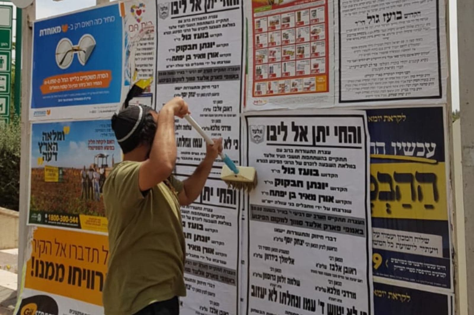 עובד הדבקה מדביק מודעה חדשה על לוח מודעות