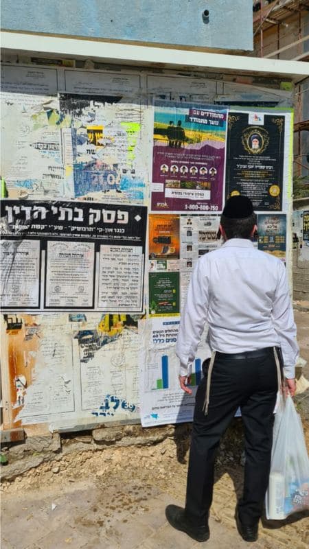 עובר אורח קורא מודעות על לוח מודעות עירוני