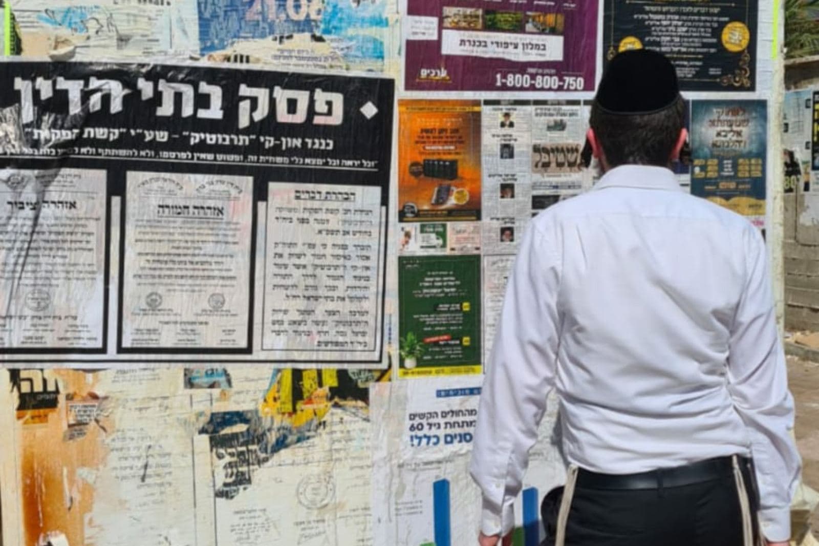 אברך עוצר לקרוא את לוח המודעות ברחוב